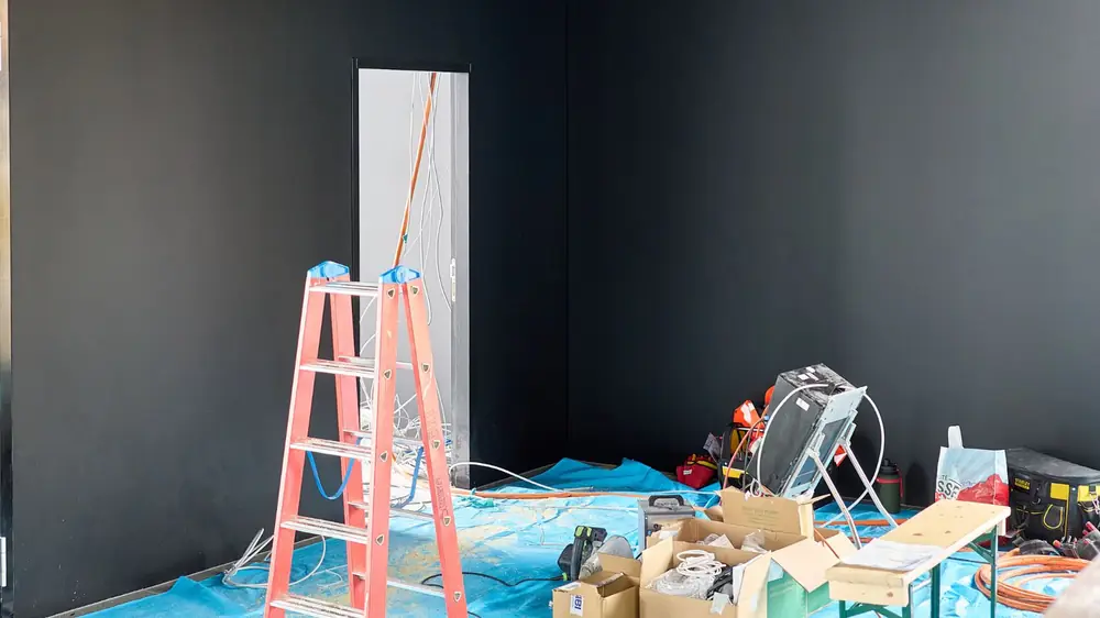Room prepared for work with plastic sheeting on the floor, a ladder and equipment